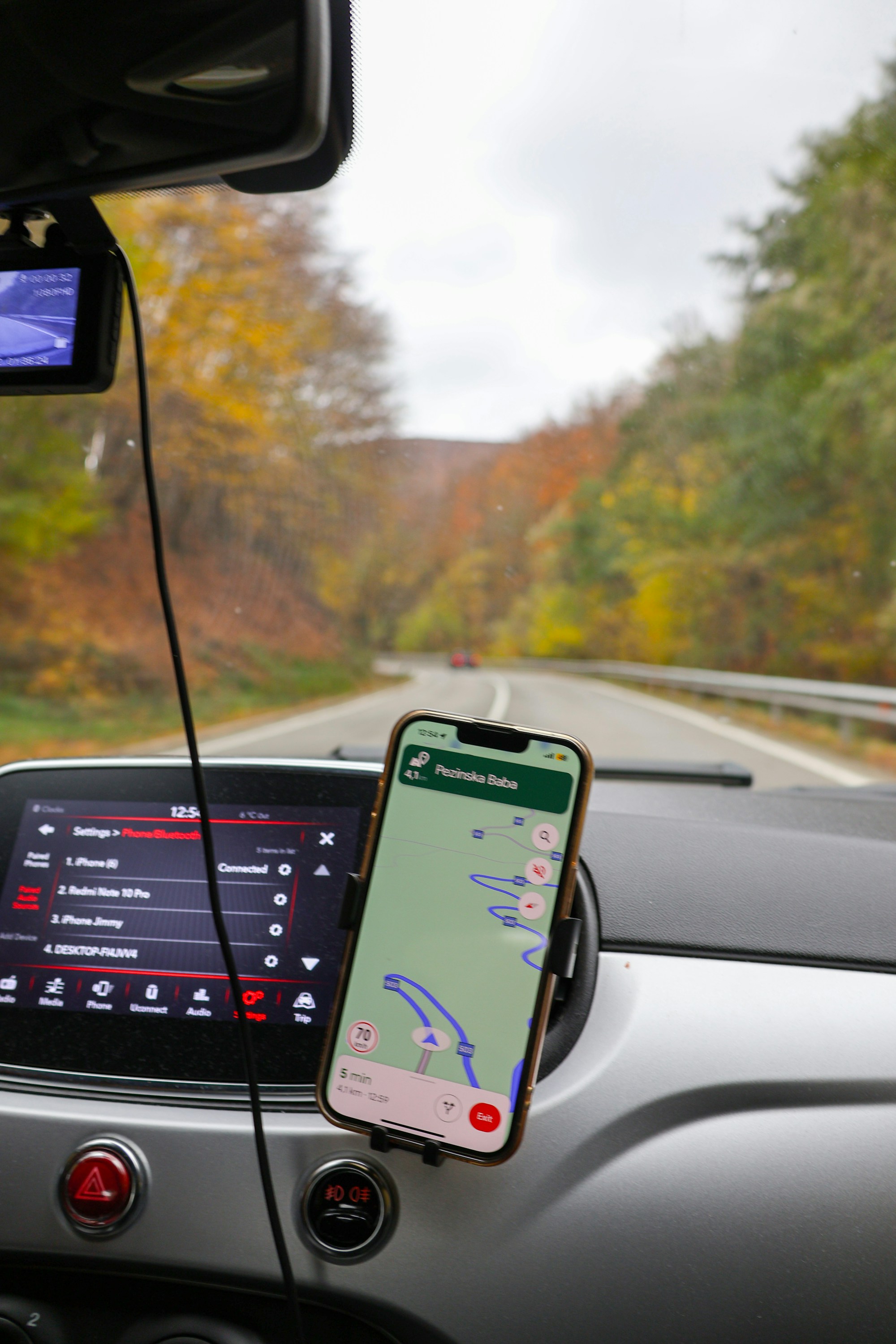 A smartphone mounted beside a car infotainment system with Bluetooth settings visible. Photo by your_mamacita on Unsplash.