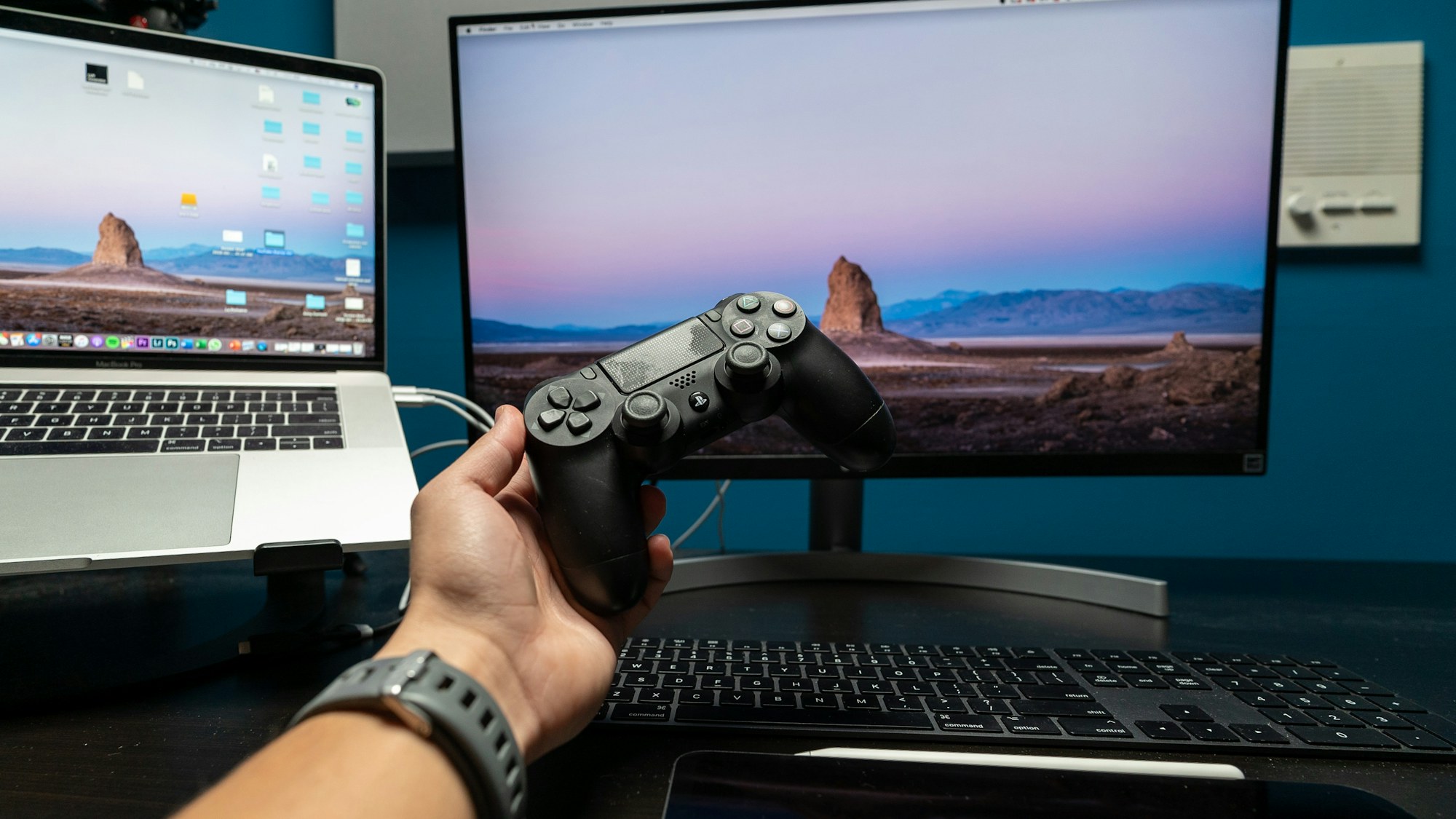 A person holding a game controller in front of a computer gaming setup. Photo by Gio Rosado on Unsplash.